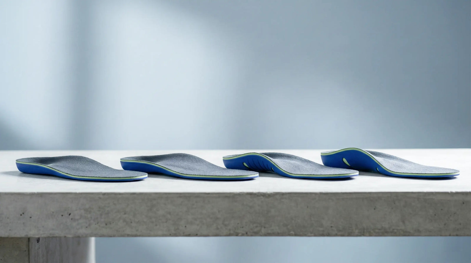 Four-stage arch support break-in timeline chart beside shoe and insole on clean desk